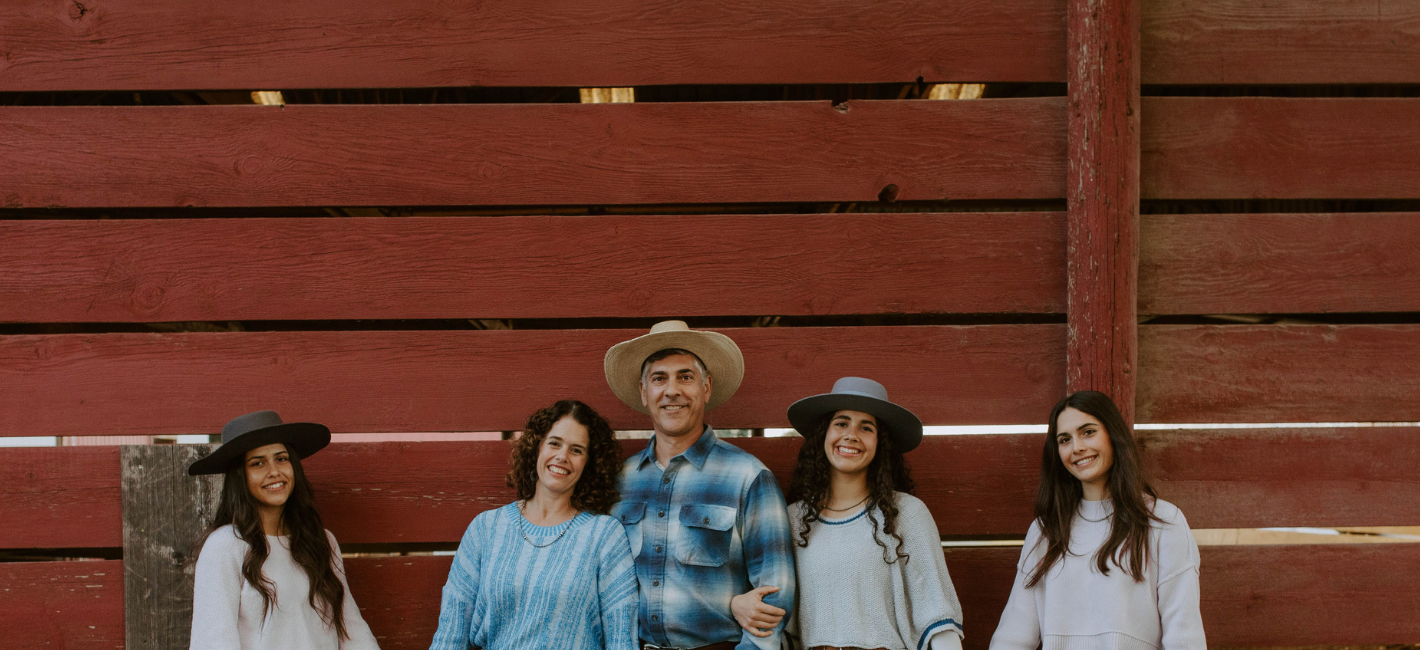 Family of five standing in front of a red wooden wall