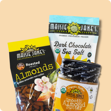 Three packages of Maisie Jane's products including almonds, dark chocolate sea salt, and almond butter on a beige background.