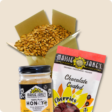 Box of raw almonds, jar of honey, and package of chocolate-coated cherries with Maisie Jane's branding.