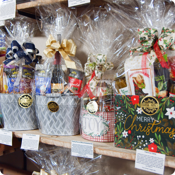 Assorted Maisie Jane's gift baskets with several being Christmas-themed packaging on a shelf.