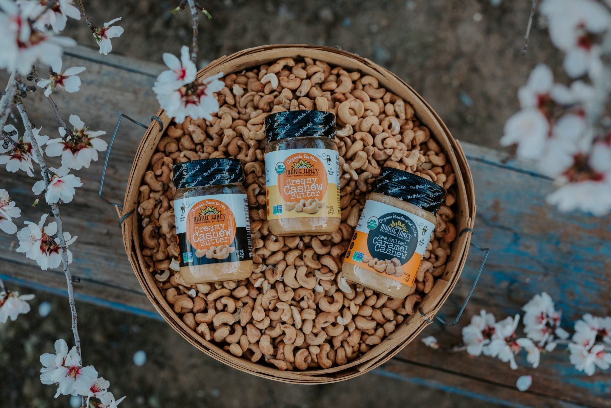 three jars of almond butter in a basket of nuts