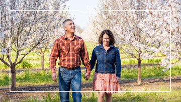 Maisie and Isidro walking in an almond orchard in bloom