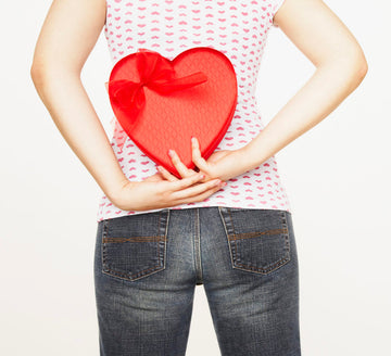 Woman holding a heart gift behind her back