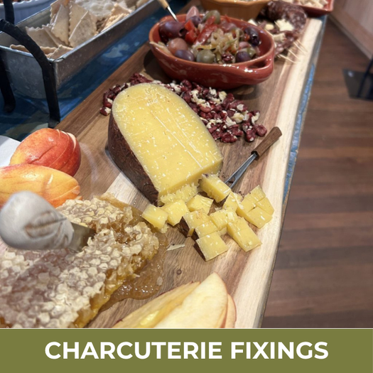 Wooden charcuterie board with various food items including cheese, fruits, and meats on a wooden surface.