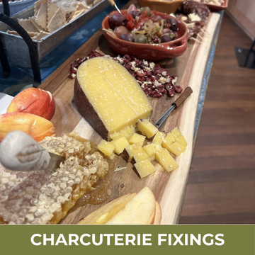 Wooden charcuterie board with various food items including cheese, fruits, and meats on a wooden surface.