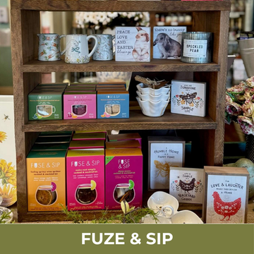 Wooden shelf with various tea boxes, mugs, and decorative items with 'FUZE & SIP' branding.