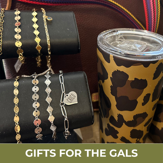 Jewelry set with gold and silver bracelets on black cylindrical stands next to a leopard print tumbler with 'Gifts for the Gals' text underneath 