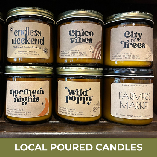 Row of candles with labels on a shelf, featuring 'Local Poured Candles' text at the bottom.